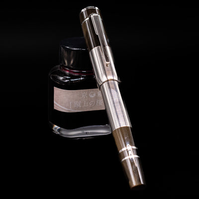 Montblanc Writer's Edition William Faulkner Fountain Pen - Preowned  capped, leaning against an ink bottle. 