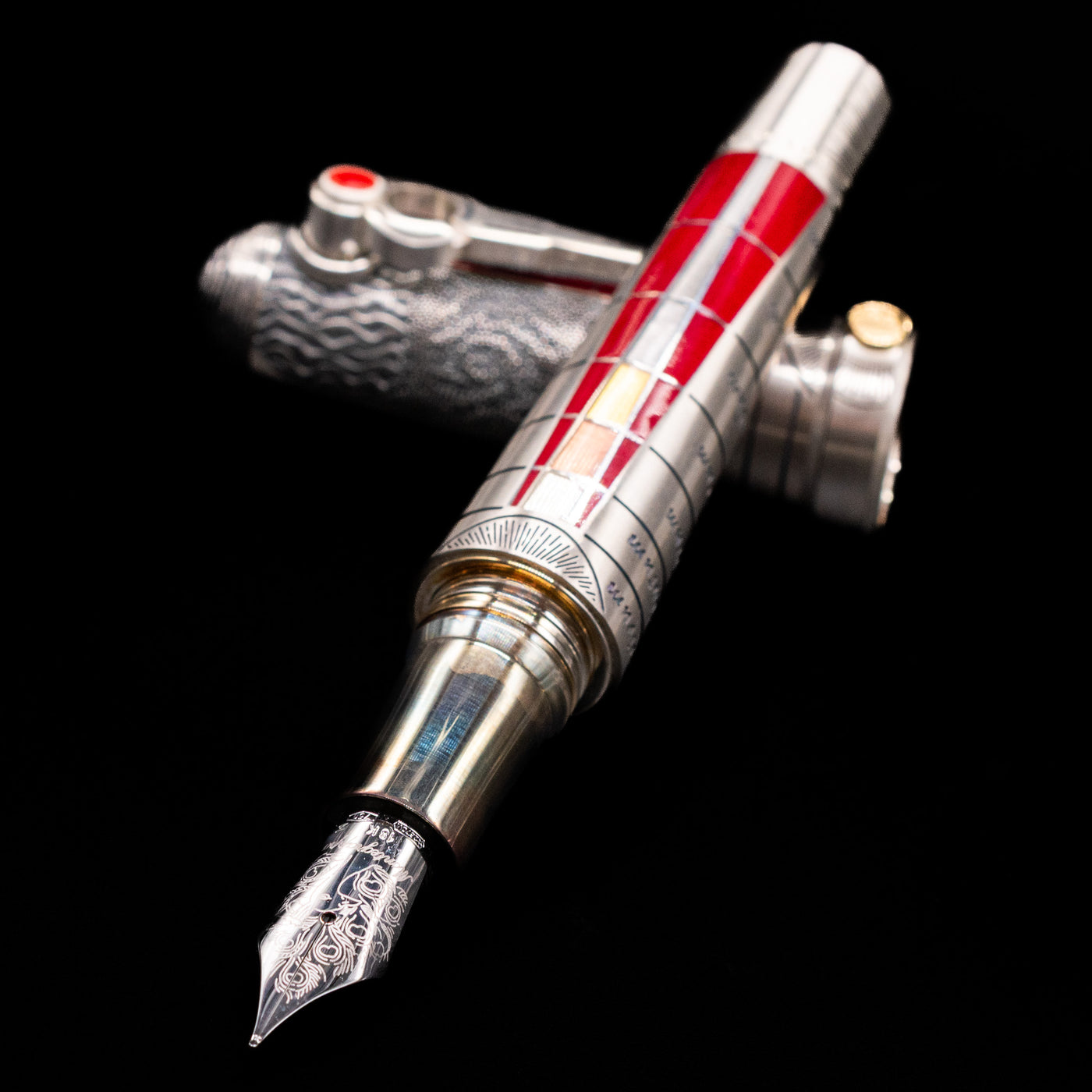 Montegrappa Alchemist Ignis Fountain Pen laying across its own cap, crossed, with a focus on the nib.