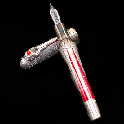 Montegrappa Alchemist Ignis Fountain Pen laying on top of its cap in a crossed position showing full view of the entire uncapped pen.