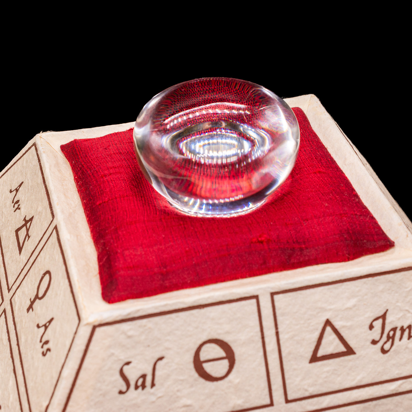 The opened alchemic pyramid showcasing the glass loop on the red pillow of the Montegrappa Alchemist Ignis Rollerball Pen.
