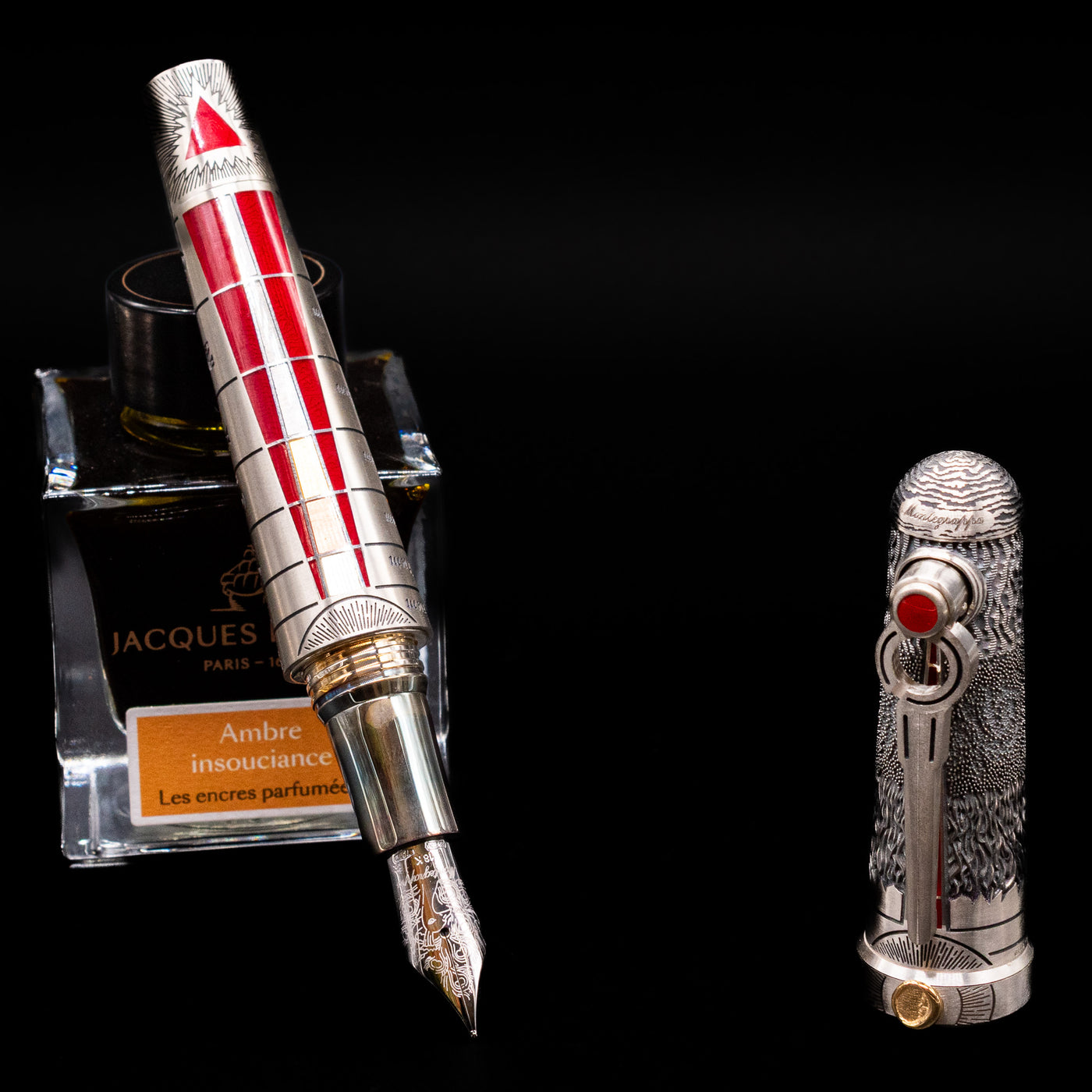 Montegrappa Alchemist Ignis Fountain Pen leaning on an ink bottle uncapped showcasing the detailing on the nib.