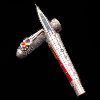 Montegrappa Alchemist Ignis Rollerbal Pen laying on top of its cap in a crossed position showing full view of the entire uncapped pen.