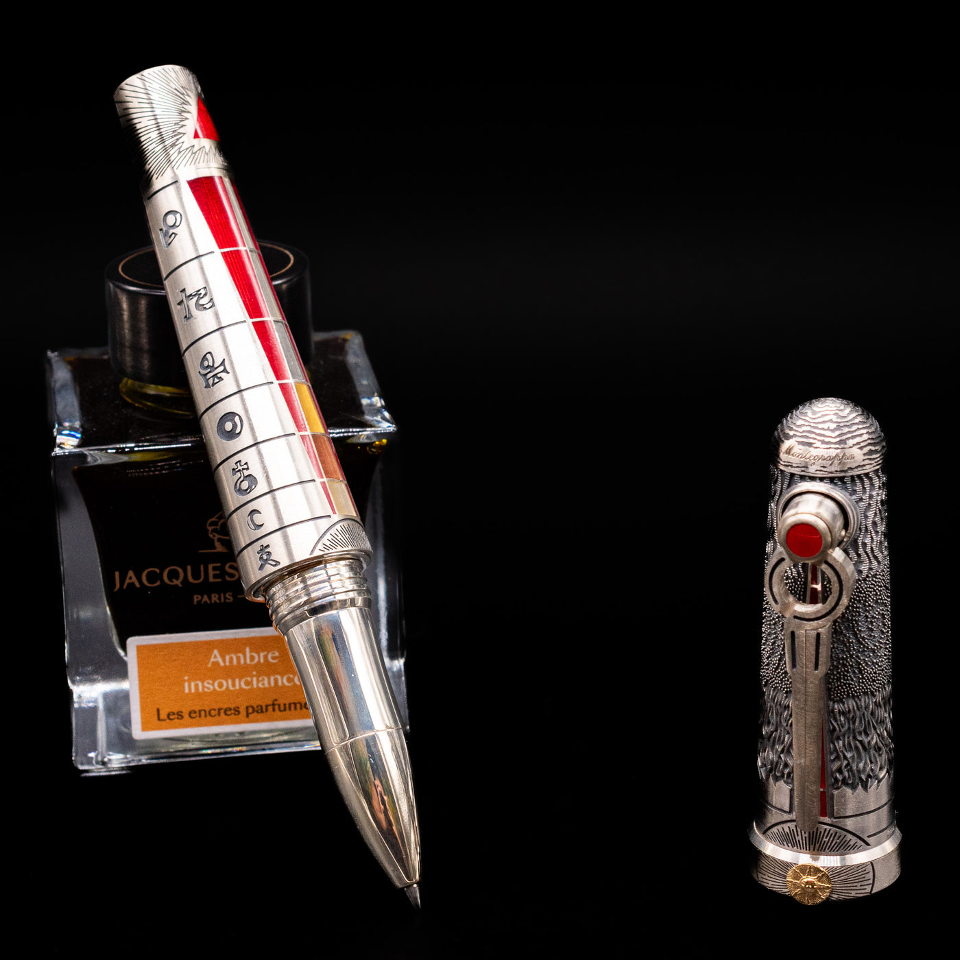 Montegrappa Alchemist Ignis Rollerbal Pen leaning on an ink bottle uncapped showcasing the detailing on the tip.