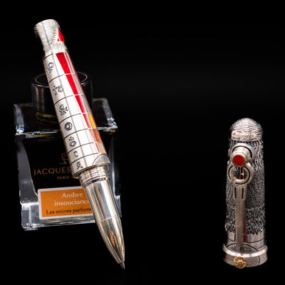 Montegrappa Alchemist Ignis Rollerbal Pen leaning on an ink bottle uncapped showcasing the detailing on the tip.