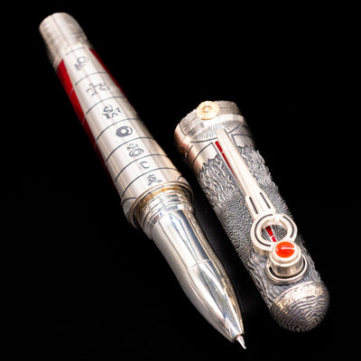 A full view of the Montegrappa Alchemist Ignis Rollerbal Pen uncapped, with its cap laying next to the pen. 