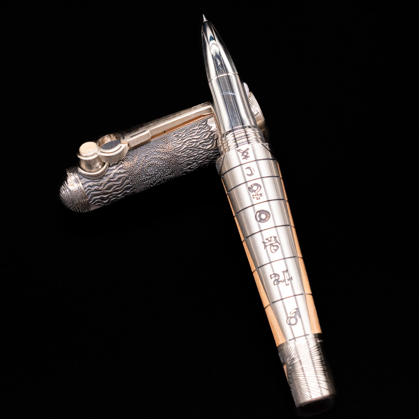 Montegrappa Alchemist Terra Rollerball Pen laying on top of its cap in a crossed position showing full view of the entire uncapped pen.
