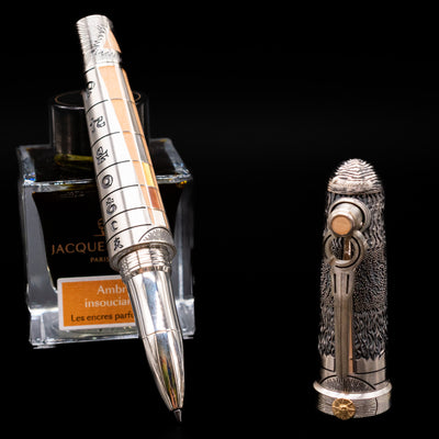 Montegrappa Alchemist Terra Rollerball Pen leaning on an ink bottle uncapped showcasing the detailing on the tip.