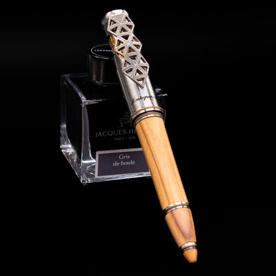 Montegrappa Leonardo da Vinci 500th Anniversary Fountain Pen capped, leaning against an ink bottle. 