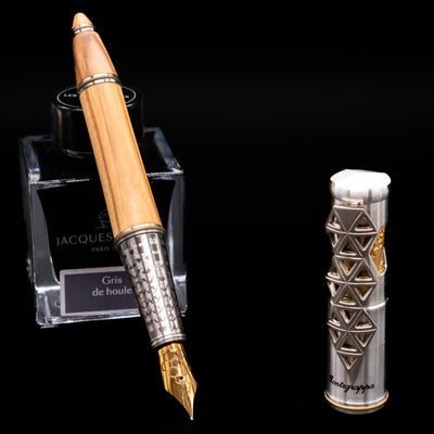 Montegrappa Leonardo da Vinci 500th Anniversary Fountain Pen leaning on an ink bottle uncapped showcasing the detailing on the nib.