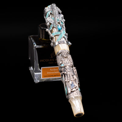 Montegrappa My Guardian Angel Fountain Pen capped and leaning on an ink bottle.