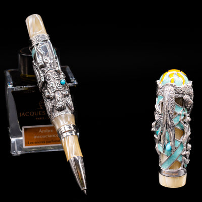 Montegrappa My Guardian Angel Rollerbal Pen leaning on an ink bottle uncapped.