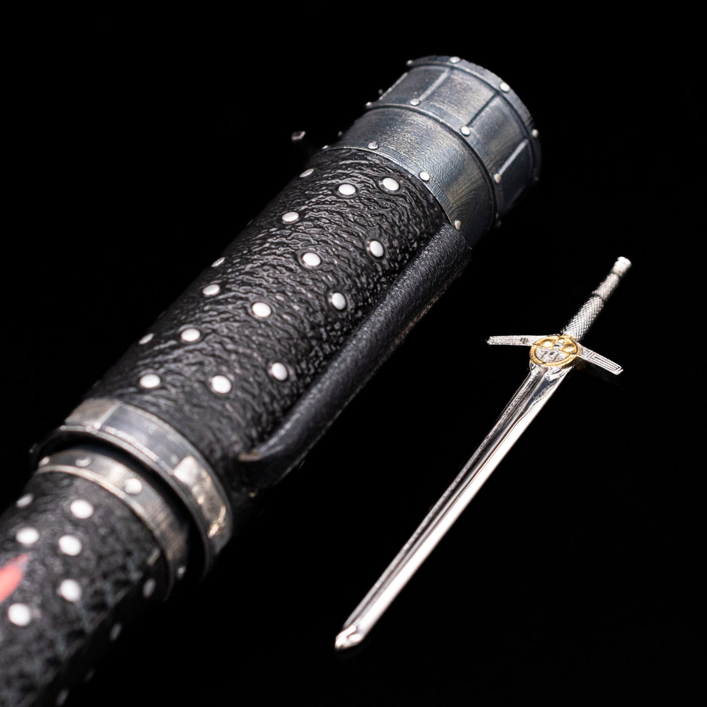 The sword unsheathed laying by the side of the Montegrappa The Witcher: Mutation Fountain Pen.