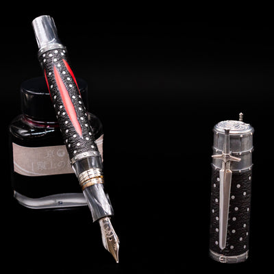 Montegrappa The Witcher: Mutation Fountain Pen leaning on an ink bottle uncapped showcasing the detailing on the nib.