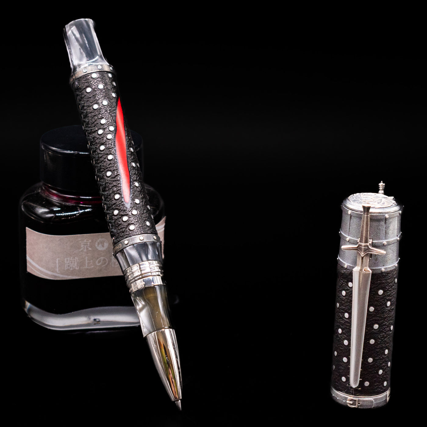 Montegrappa The Witcher: Mutation Rollerbal Pen leaning on an ink bottle uncapped.