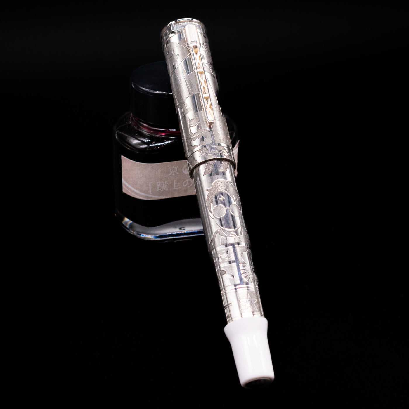 Montegrappa Warner Brothers 100th Anniversary Fountain Pen capped, leaning against an ink bottle. 