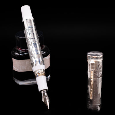 Montegrappa Warner Brothers 100th Anniversary Fountain Pen leaning on an ink bottle uncapped showcasing the detailing on the nib.