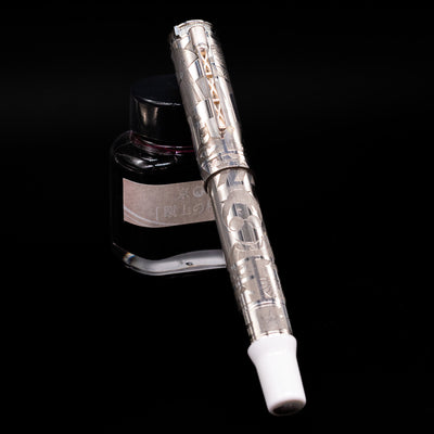 Montegrappa Warner Brothers 100th Anniversary Rollerball Pen capped, leaning against an ink bottle. 
