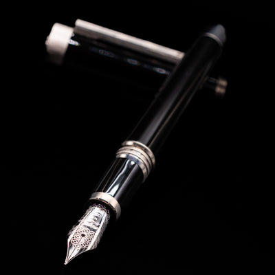 Montegrappa Zero Black & Palladium Fountain Pen - Preowned laying across its own cap, crossed, with a focus on the nib.