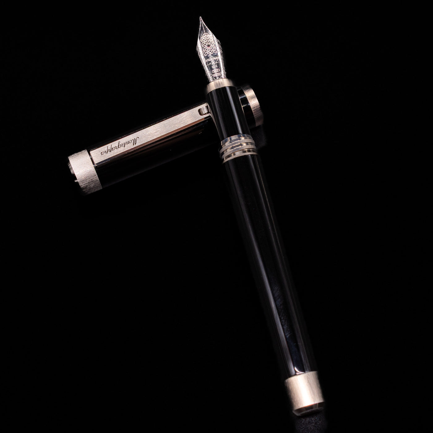 Montegrappa Zero Black & Palladium Fountain Pen - Preowned laying on top of its cap in a crossed position showing full view of the entire uncapped pen.