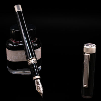 Montegrappa Zero Black & Palladium Fountain Pen - Preowned leaning on an ink bottle uncapped showcasing the detailing on the nib.