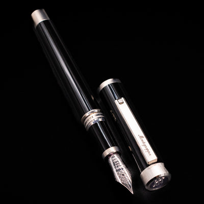 A full view of the Montegrappa Zero Black & Palladium Fountain Pen - Preowned uncapped, with its cap laying next to the pen. 