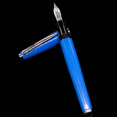 Monteverde Aldo Domani Italia Fountain Pen - Exotic Blue laying on top of its cap in a crossed position showing full view of the entire uncapped pen.