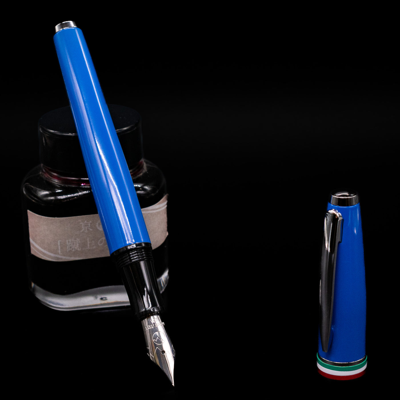 Monteverde Aldo Domani Italia Fountain Pen - Exotic Blue leaning on an ink bottle uncapped showcasing the detailing on the nib.