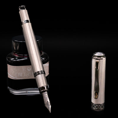 Monteverde Innova Fountain Pen - Titanium leaning on an ink bottle uncapped showcasing the detailing on the nib.