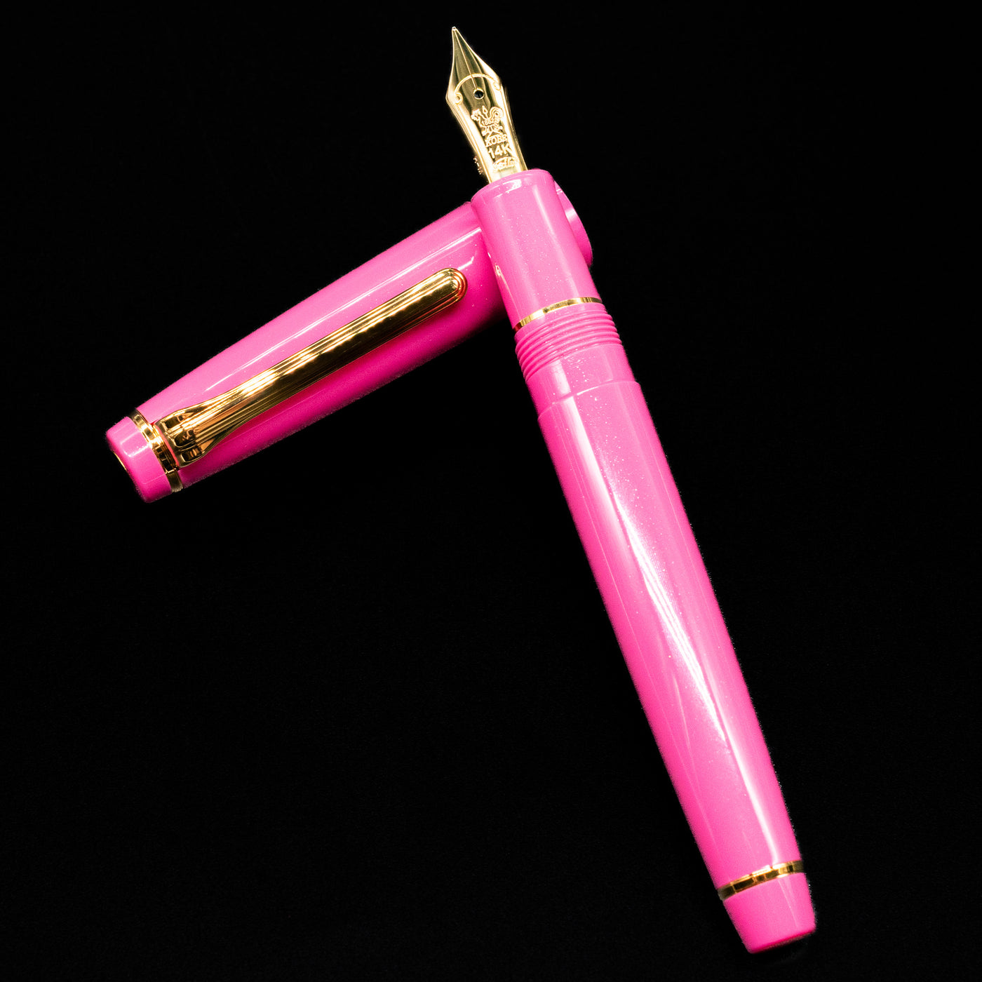 Nagasawa Original Fountain Pen - Suma-Rikyu Rose laying on top of its cap in a crossed position showing full view of the entire uncapped pen.