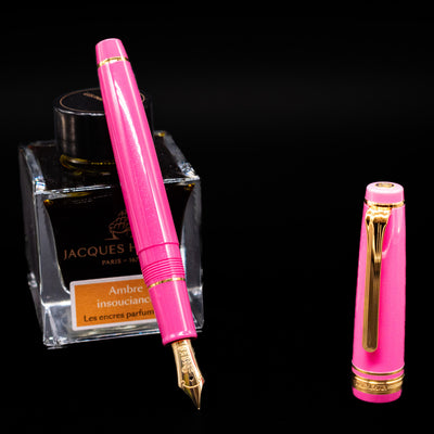 Nagasawa Original Fountain Pen - Suma-Rikyu Rose leaning on an ink bottle uncapped showcasing the detailing on the nib.