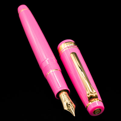 A full view of the Nagasawa Original Fountain Pen - Suma-Rikyu Rose uncapped, with its cap laying next to the pen. 