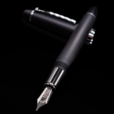Nagasawa Original Large Fountain Pen - Black & Silver FL (For Lawyer) laying across its own cap, crossed, with a focus on the nib.
