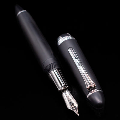 A full view of the Nagasawa Original Large Fountain Pen - Black & Silver FL (For Lawyer) uncapped, with its cap laying next to the pen. 