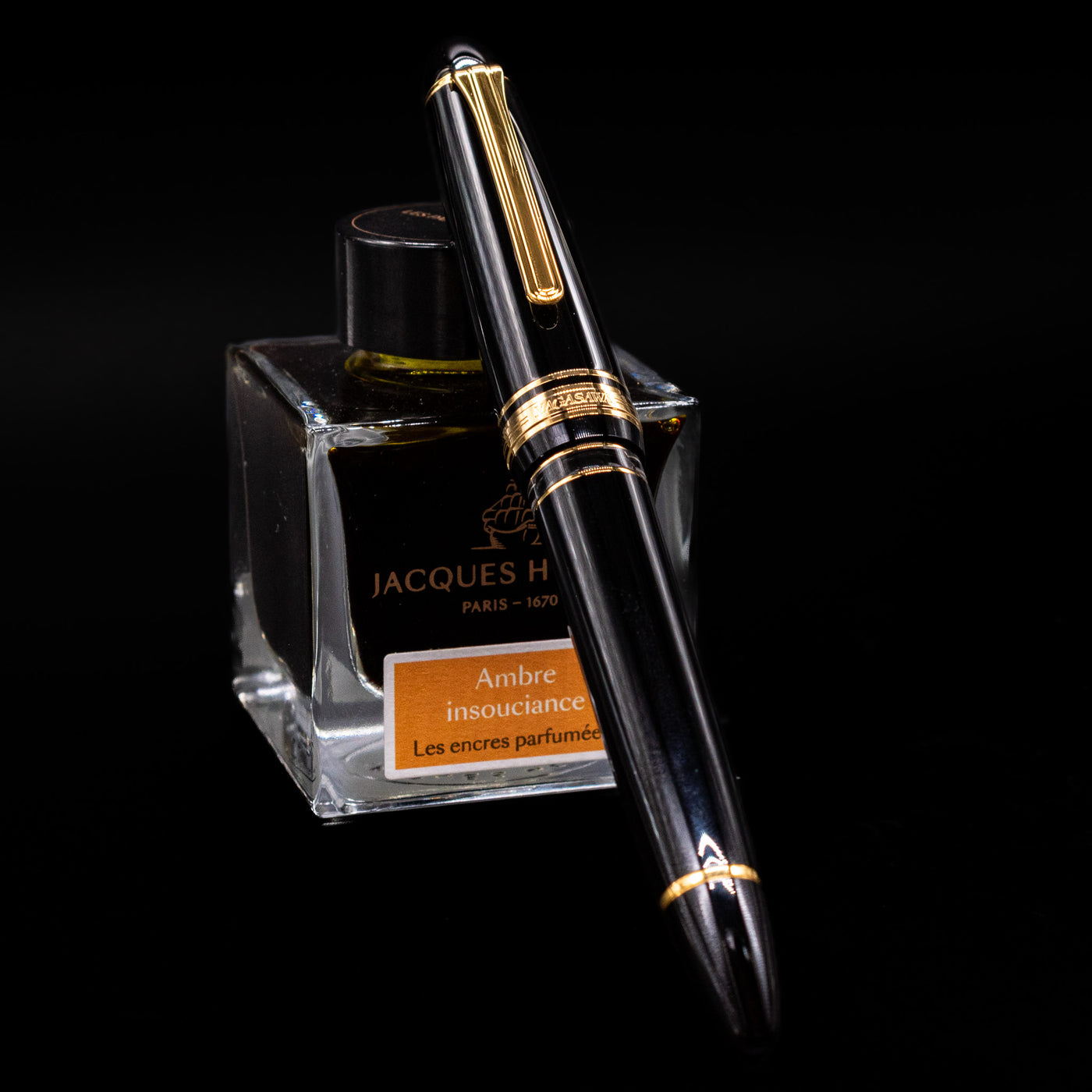 Nagasawa Original Large Piston Fountain Pen - Realo FL (For Lawyer) capped, leaning against an ink bottle. 