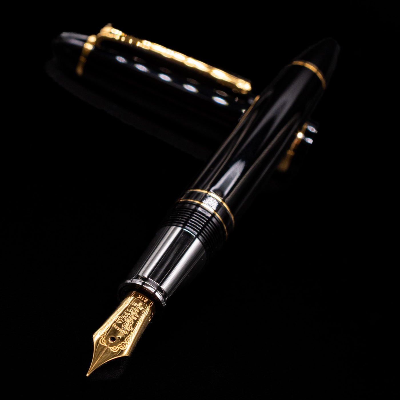 Nagasawa Original Large Piston Fountain Pen - Realo FL (For Lawyer) laying across its own cap, crossed, with a focus on the nib.