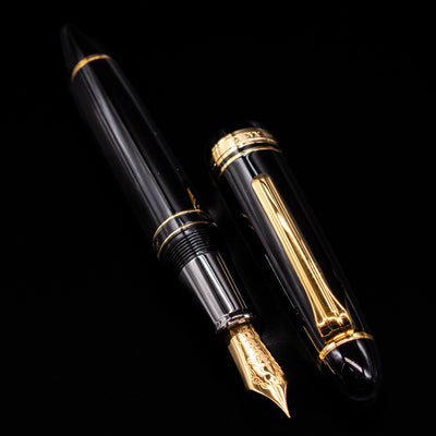 A full view of the Nagasawa Original Large Piston Fountain Pen - Realo FL (For Lawyer) uncapped, with its cap laying next to the pen. 