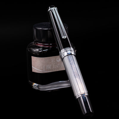 Nagasawa Original Limited Edition Fountain Pen - Engrave Kou capped, leaning against an ink bottle. 