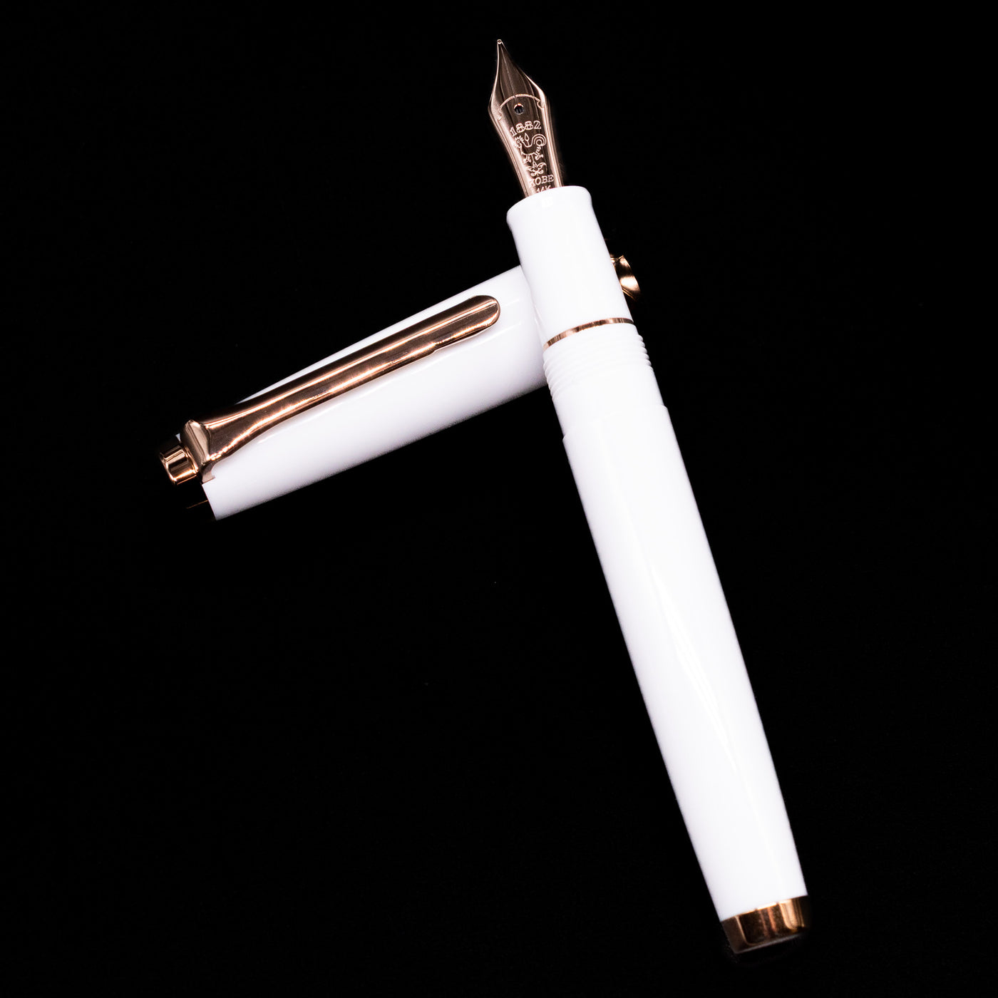 Nagasawa Original Limited Edition Fountain Pen - Odyssey Snow White laying on top of its cap in a crossed position showing full view of the entire uncapped pen.