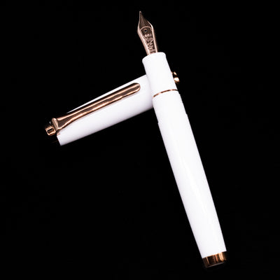 Nagasawa Original Limited Edition Fountain Pen - Odyssey Snow White laying on top of its cap in a crossed position showing full view of the entire uncapped pen.