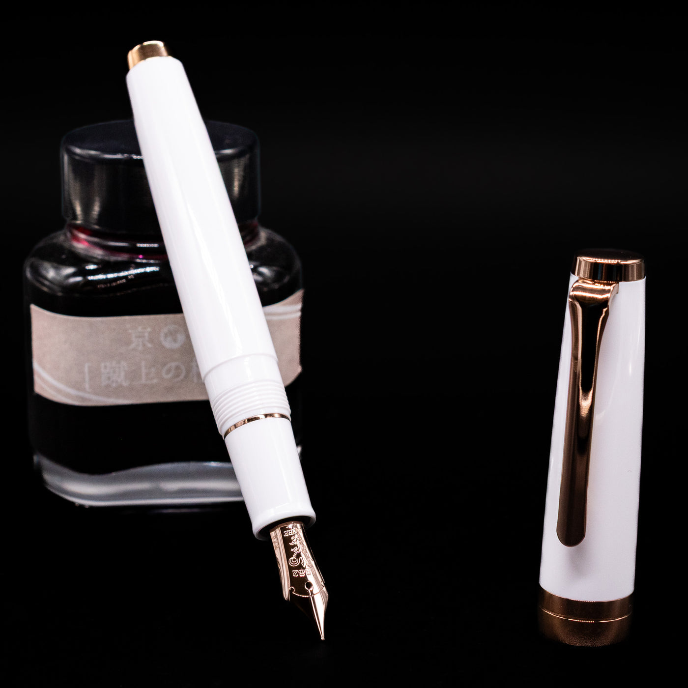 Nagasawa Original Limited Edition Fountain Pen - Odyssey Snow White  leaning on an ink bottle uncapped showcasing the detailing on the nib.