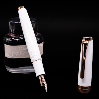 Nagasawa Original Limited Edition Fountain Pen - Odyssey Snow White  leaning on an ink bottle uncapped showcasing the detailing on the nib.