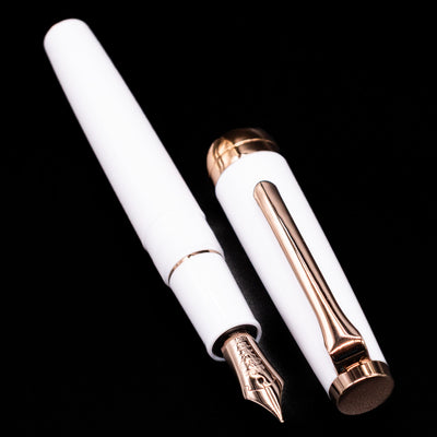 A full view of the Nagasawa Original Limited Edition Fountain Pen - Odyssey Snow White uncapped, with its cap laying next to the pen. 