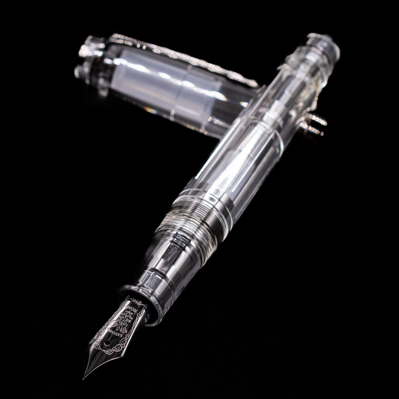 Nagasawa Original Professional Gear Fountain Pen - Skeleton Black laying across its own cap, crossed, with a focus on the nib.