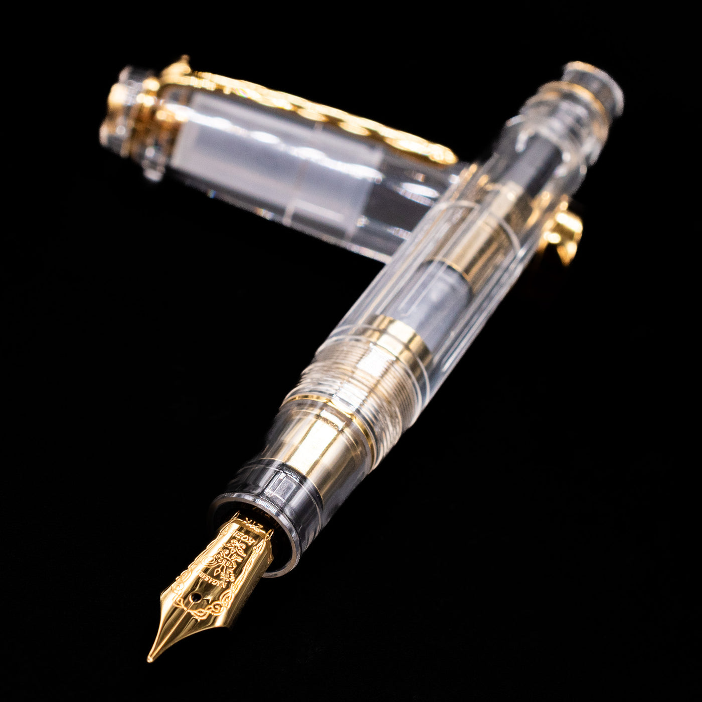 Nagasawa Original Professional Gear Fountain Pen - Skeleton Gold laying across its own cap, crossed, with a focus on the nib.