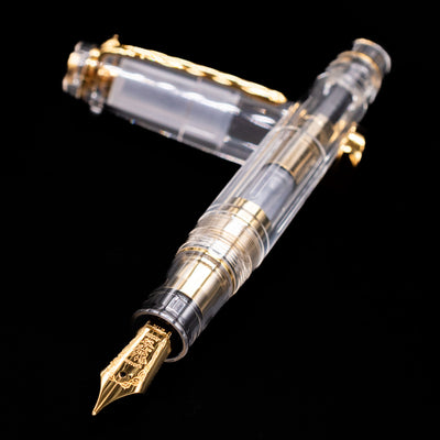 Nagasawa Original Professional Gear Fountain Pen - Skeleton Gold laying across its own cap, crossed, with a focus on the nib.