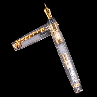 Nagasawa Original Professional Gear Fountain Pen - Skeleton Gold laying on top of its cap in a crossed position showing full view of the entire uncapped pen.