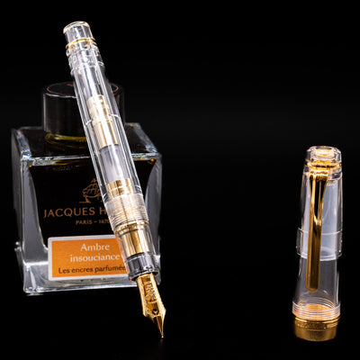 Nagasawa Original Professional Gear Fountain Pen - Skeleton Gold leaning on an ink bottle uncapped showcasing the detailing on the nib.