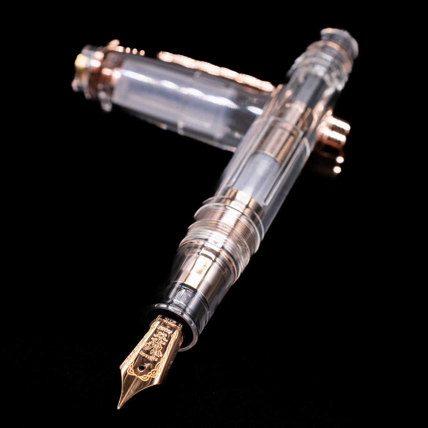 Nagasawa Original Professional Gear Fountain Pen - Skeleton Pink Gold laying across its own cap, crossed, with a focus on the nib.
