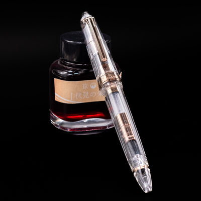 Nagasawa Original Standard Fountain Pen - Skeleton Proske Antique Gold
capped, leaning against an ink bottle. 