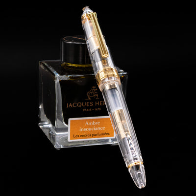 Nagasawa Original Standard Fountain Pen - Skeleton Proske Gold capped, leaning against an ink bottle.